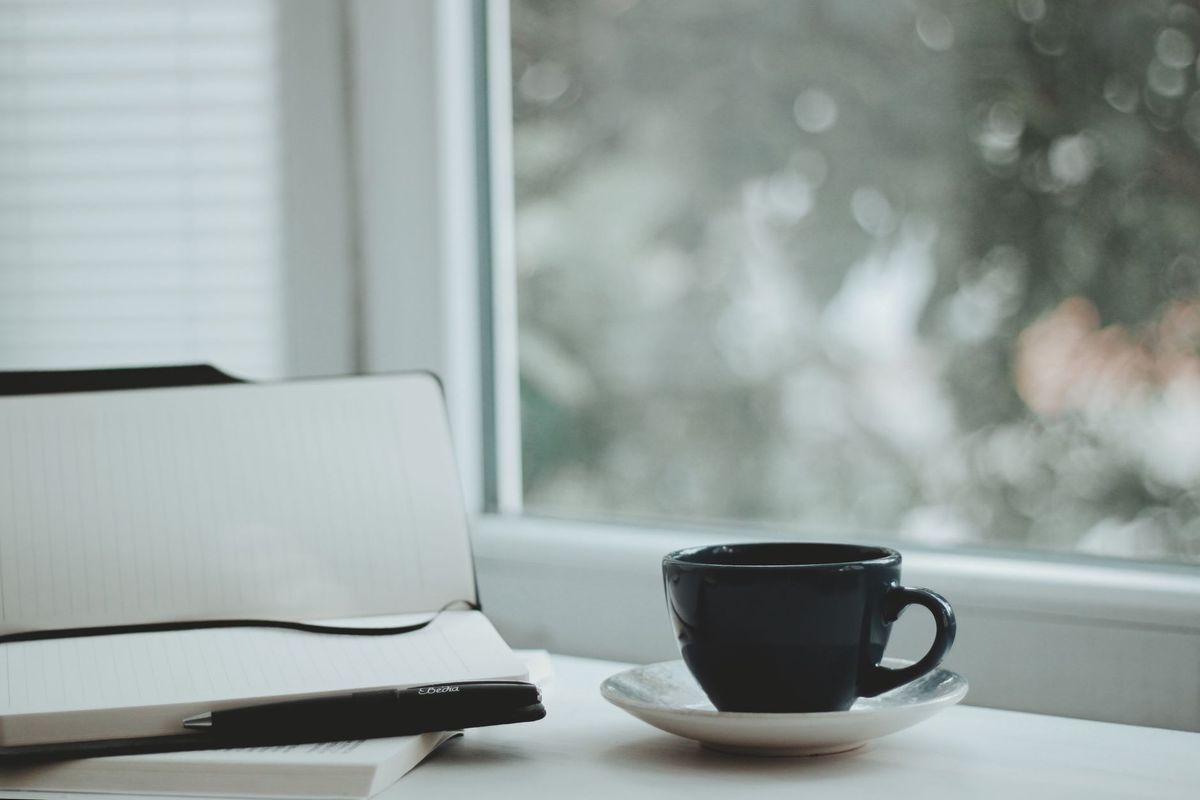 Notebook and coffee beside a bright window