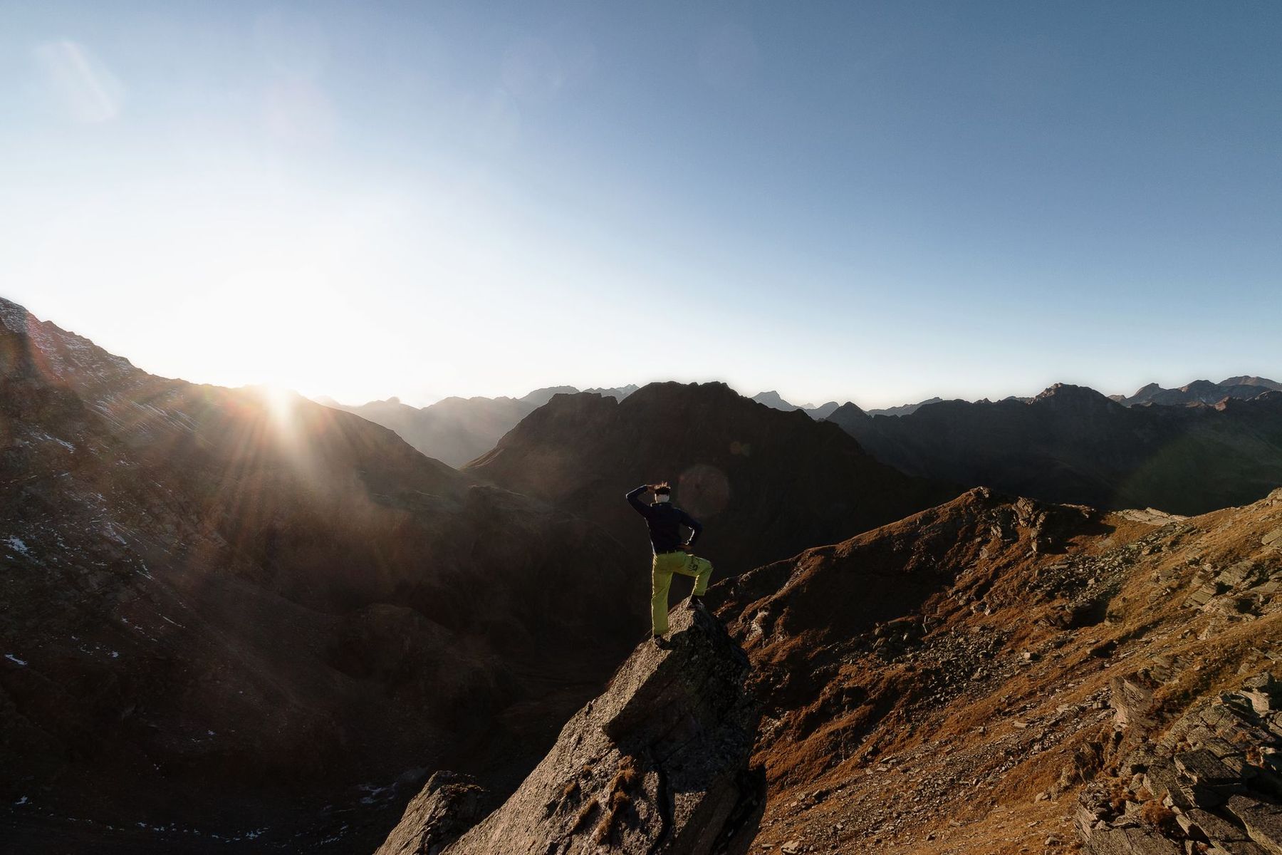 Hiker standing on a mountain ridge at dawn